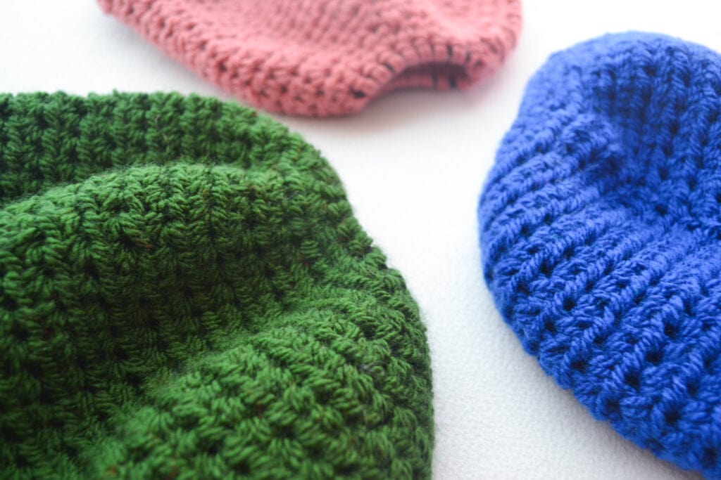 close up shot showing the tops of 3 crochet messy bun beanies