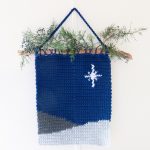 Square featured image of this dark blue and grey crochet wall hanging, with a white star design