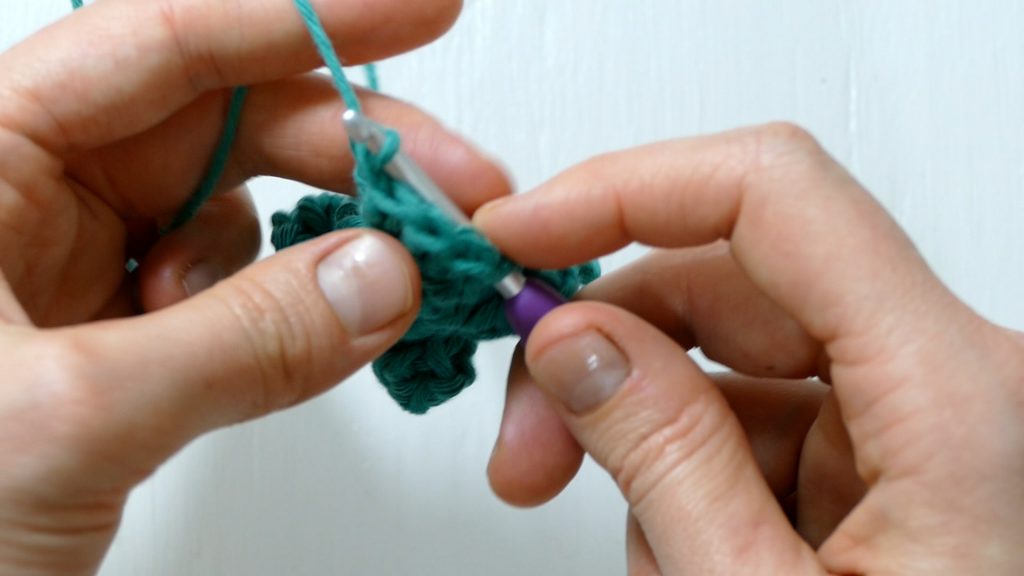 Showing how to grab a loop of yarn to draw the crochet bobble closed