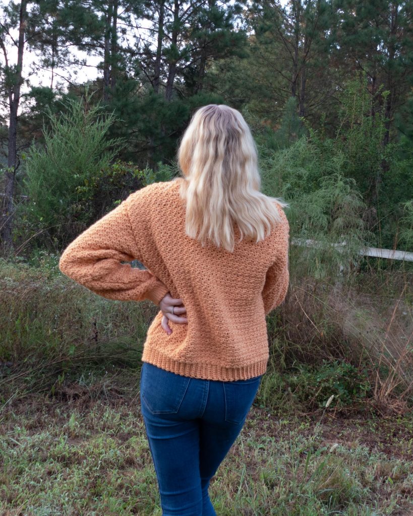 Back of a textured crochet sweater in orange color