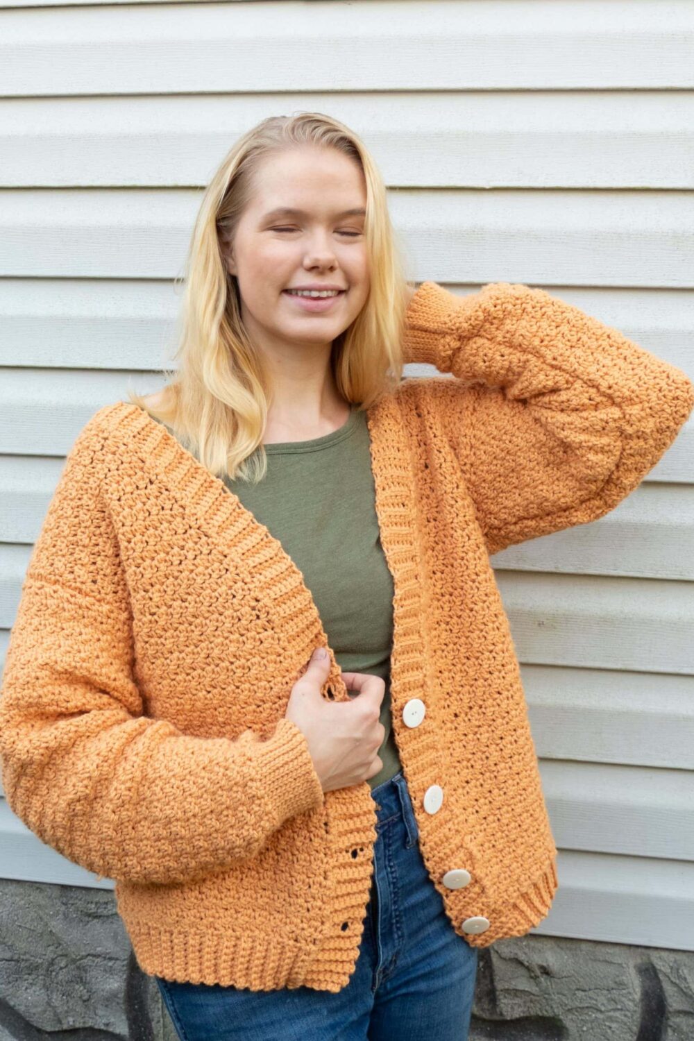 modeling a light orange crochet cardigan outdoors