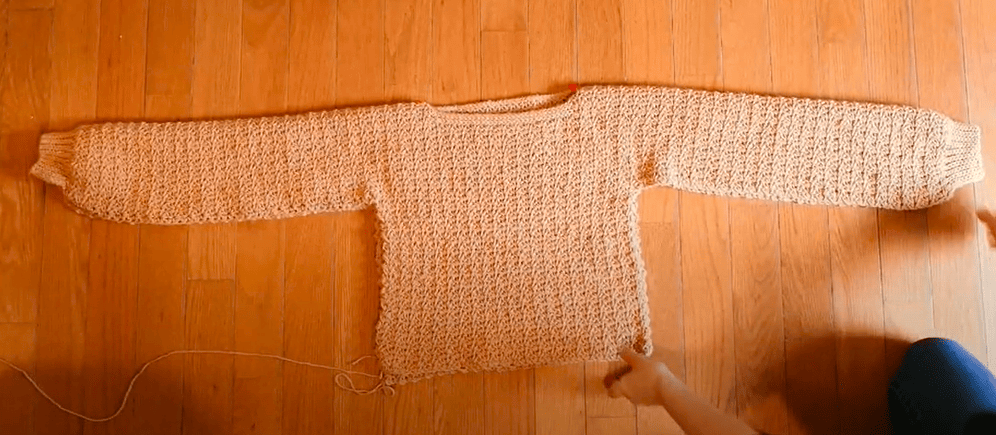 The textured turnover crochet sweater laying on the ground, folded over and ready to be seamed up.