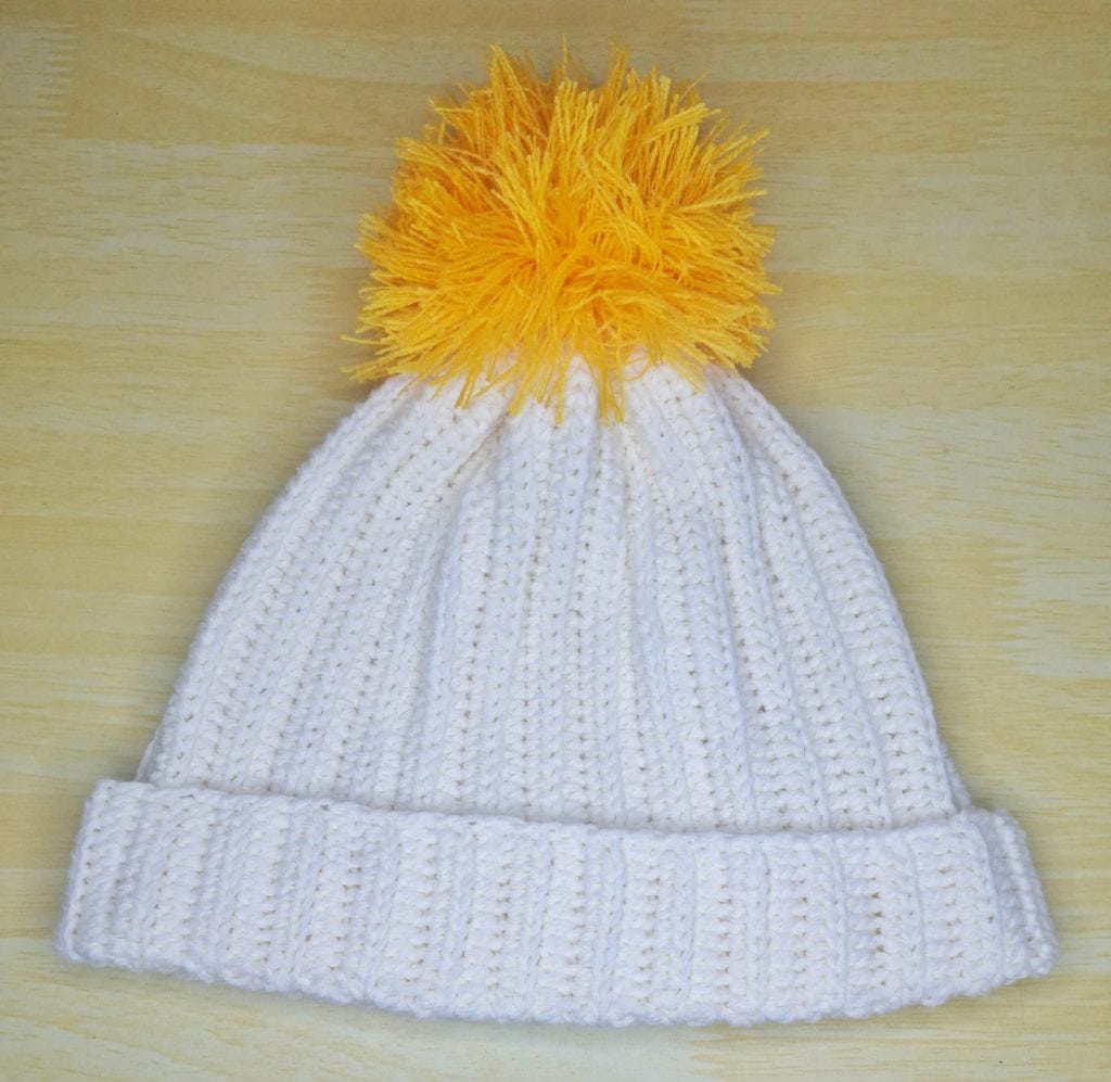A white crochet ribbed hat with a pom pom